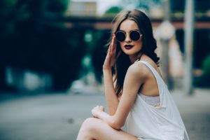 beautiful girl in sunglasses sitting on the asphalt